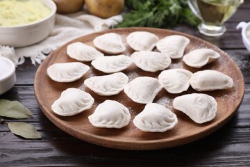 Fototapeta na wymiar Raw dumplings (varenyky) and ingredients on brown wooden table