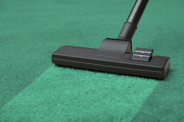 Vacuuming dirty green carpet. Clean area after using device, closeup