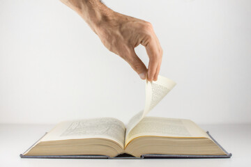 Man's hand turning the page of an old book.