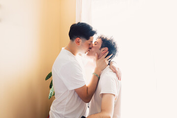 Two gay men wearing white t shirts, romantically kissing on the mouth. LGBT relationship 