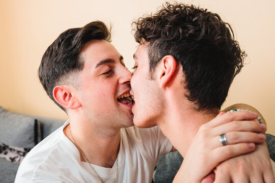 Close up of a gay couple romantically kissing on the mouth, playing and smiling. LGBT relationship 