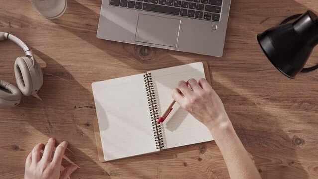 Top down view of a woman's hands writing the title PEACE in notebook and drawing icon. concept no war. peaceful inscription in notebook. international sign of peace and love, hippies.