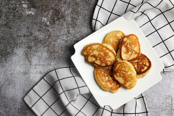Cottage cheese pancakes on a white square  plate on a dark background. Top view, flat lay