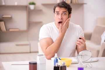 Young man shaving face at home
