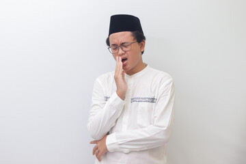 Portrait of young Asian muslim man yawning with hand covering his mouth. Isolated image on white...
