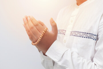 Close up of male hands raising and praying with islamic beads. Religion concept