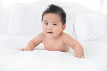 Baby boy wearing diaper in white sunny bedroom. newborn child relaxing in bed. nursery for children. textile and bedding for kids. family morning at home.