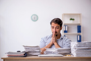 Young male employee unhappy with excessive work in the office