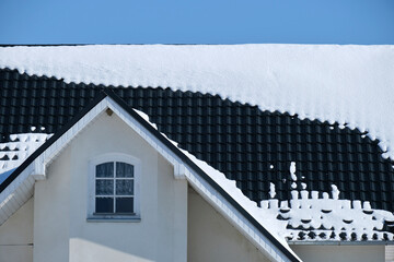 Closeup of house roof top covered with snow in cold winter. Tiled covering of building in...