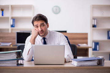 Young male employee unhappy with excessive work in the office