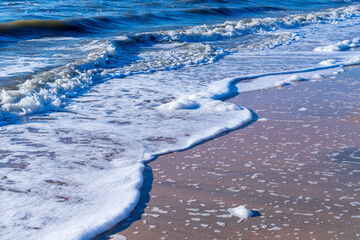 Image of sea foam on a sandy beach.