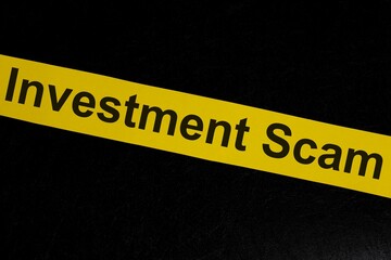 Investment scam and fraud alert, caution and warning concept. Yellow barricade tape with word in...