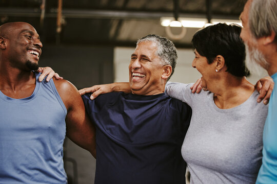 Senior people, fitness group and support for training, workout and exercise community or club in gym. Laugh, black people and elderly diversity friends with sports wellness hug together for teamwork