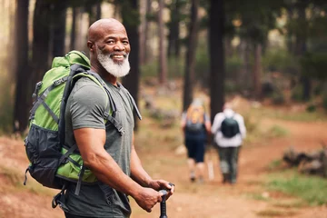 Fotobehang Portrait, black man and hiking in forest, exercise and fitness for wellness, healthy lifestyle and smile. Face, senior male and mature gentleman with backpack, smile and hiker in woods and fresh air © Azee J/peopleimages.com