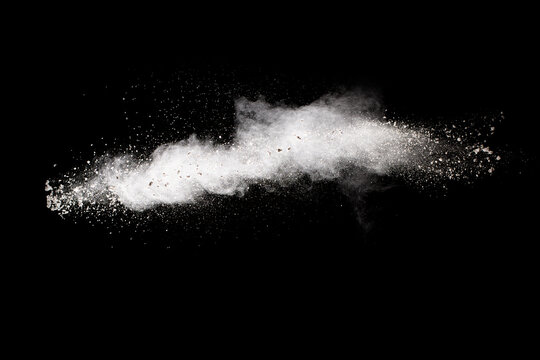 White powder explosion cloud against black background. White dust particles splash.