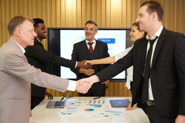 businessman shaking hands from success at work or project in front of boss in conference room