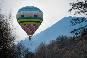 Hot air balloon with fire heating air in wicker basket with himalaya mountains in background...