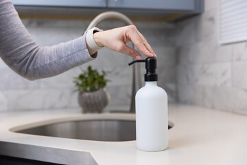 Woman refilling the soap dispencer with a funnel