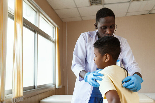 african american pediatrician doctor using stethoscope to examining boy from sickness in office at the hospital. medical and healthy.