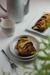 Serving pieces of marble cake on a plate with a cup of tea