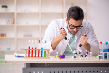 Young male chemist sitting at the lab