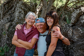 Cheerful group of caucasian senior people looking at camera while enjoying a mountain hike in the forest appreciating leisure and freedom, beautiful retired seniors and healthy lifestyle concept