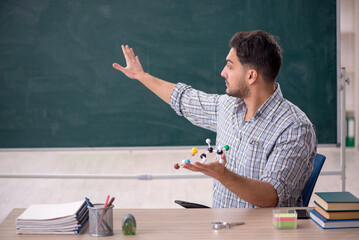 Young male teacher holding molecular model