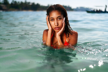 Portrait of serene looking attractive young black female posing in bikini in water. African model posing in the sea. Multiracial woman posing at the beach in ocean. Fashion portrait of black woman