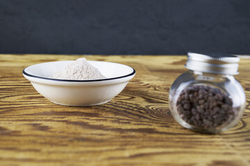 Black salt Kala namak in a glass salt shaker and on a plate on a wooden table