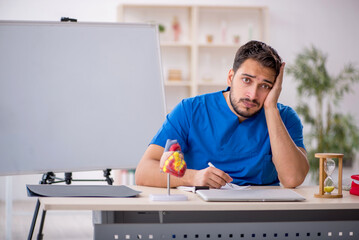 Young male doctor cardiologist in time management concept