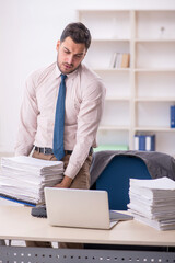 Fototapeta premium Young male employee unhappy with excessive work in the office