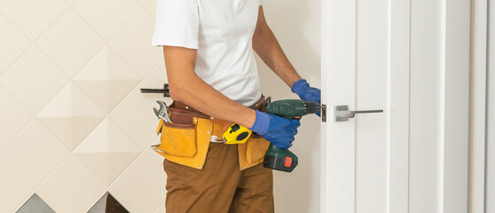 Handyman Fitting A New Door Using A Screwdriver At Home