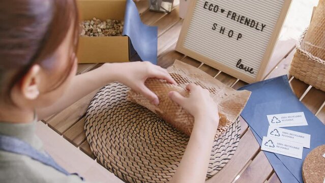 Eco vendor go green packaging parcel carton box in net zero waste store asian seller retail shop. Earth care day small SME owner asia people wrap reuse brown paper pack gift reduce plastic free order.