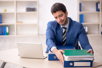 Young male employee and too much work in the office