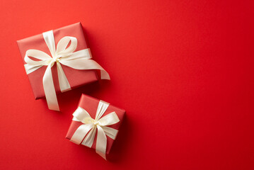 Saint Valentine's Day concept. Top view photo of present boxes with white ribbon bows on isolated red background with empty space