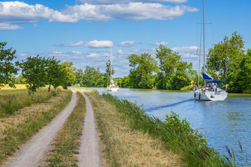 Canal with sailboats and a dirt road