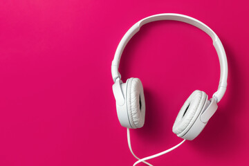 White headphones on a fuchsia color background close-up