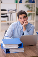 Naklejka premium Young male employee and too much work in the office