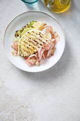 Plate with bbq cabbage steak and bacon, above view on a light-beige stone background, vertical shot with copy space