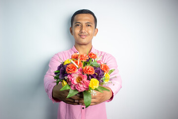 Portrait of Asian young man holding flower wearing pink shirt isolated on white background.