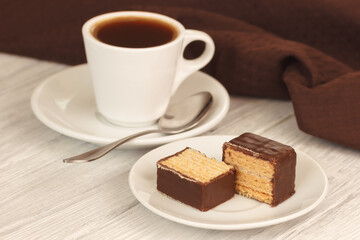 Sweet waffles in chocolate with cup of hot homemade coffee espresso on white wooden table