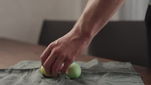 Man hand put easter eggs on a walnut table