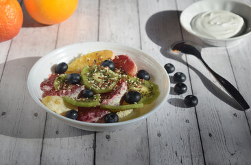 photo still life, plate with fruit salad, blueberry berries, spoon and yogurt , rustic