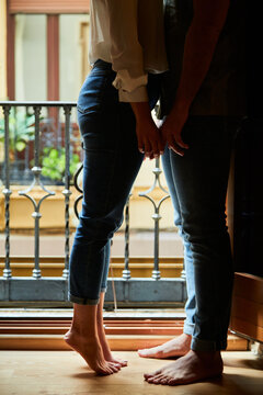Top view of young intimate couple relaxing next to a window with a balcony at home.