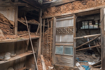 Fototapeta na wymiar Urbex, destroyed room of an abandoned traditional South-Korean house, the walls, door and windows are broken, there are remains on the floor, the room is messy, dirty and dusty