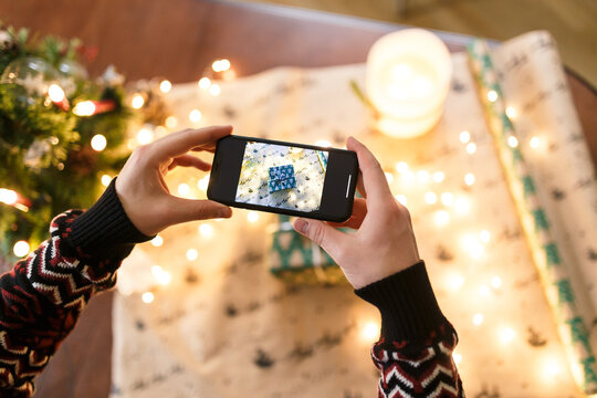 man taking pictures on smartphone carefully wrapped Christmas present