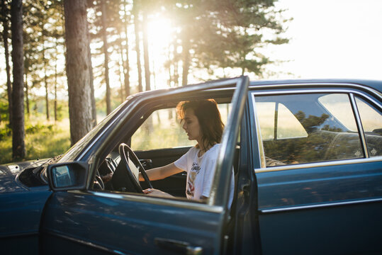 Woman sitting in a parked  broken car.