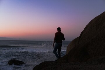 Man standing at the coast watching the sun rising