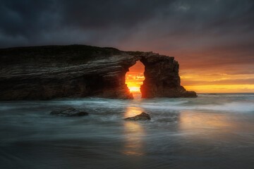 Rock arch in Las Catedrales Beach at sunset in Ribadeo, Spain