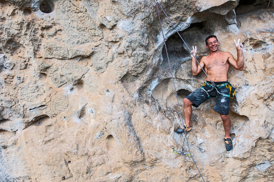 man smiling for the photographer while climbing on rock face in China